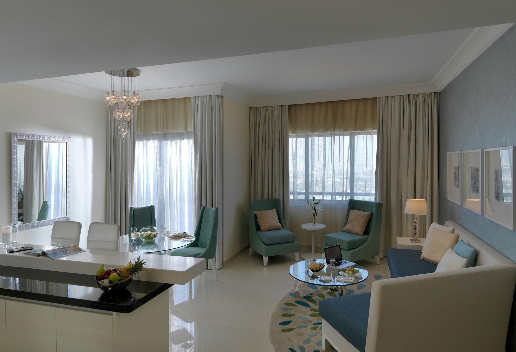 DAMAC Maison Dubai Mall Street Exterior foto The photo depicts a modern and stylish living room or lounge area. The space features large windows with sheer curtains that allow natural light to fill the room. A comfortable seating arrangement includes light blue chairs and a sofa in neutral tone
