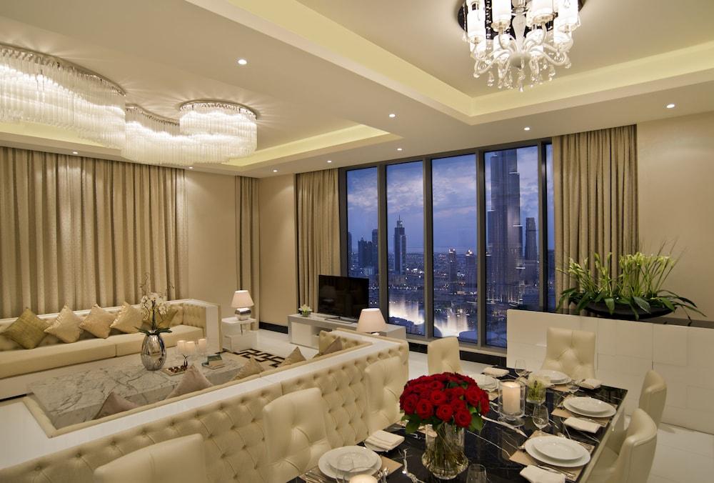 DAMAC Maison Dubai Mall Street Exterior foto The photo shows a stylish and modern living area. It features elegant furnishings, including a white sectional sofa with decorative cushions and a glass coffee table. The space has a large window with a view of the cityscape, illuminated by the eveni