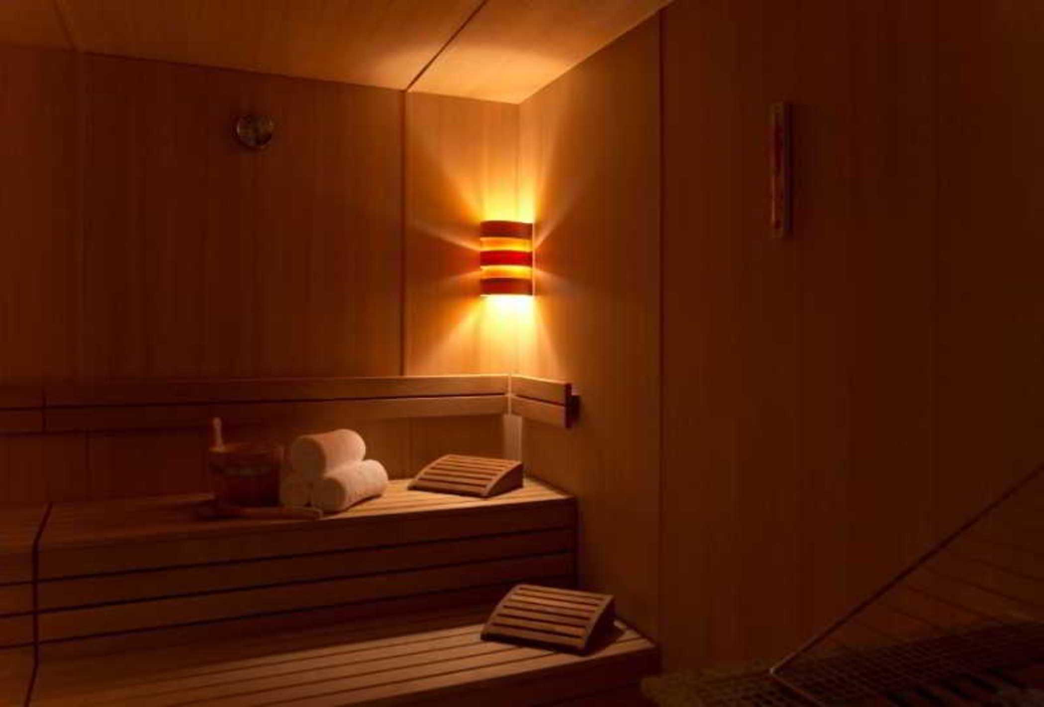DAMAC Maison Dubai Mall Street Exterior foto The image shows the interior of a sauna. The space is dimly lit, creating a warm and relaxing atmosphere. There are wooden benches arranged alongside the walls, and some rolled towels are placed on the benches. A soft light fixture mounted on the wal