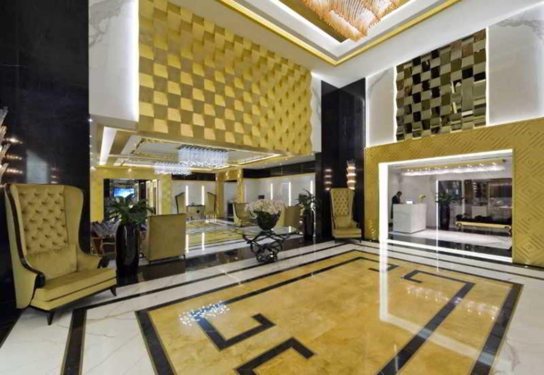 DAMAC Maison Dubai Mall Street Exterior foto The photo shows a luxurious hotel lobby with a modern and elegant design. The walls feature a combination of gold and black accents, creating a sophisticated atmosphere. There are stylish armchairs with a plush texture, positioned around a central ar