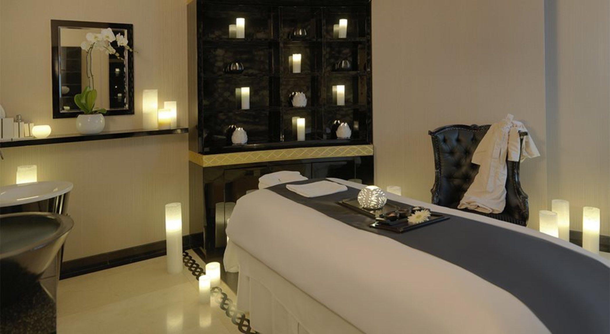 DAMAC Maison Dubai Mall Street Exterior foto The photo shows a serene and elegant spa room. In the center, there is a massage table covered with a white sheet and a dark gray runner. On the table, there is a decorative tray with a few items, possibly for relaxation or aromatherapy. Surrounding 