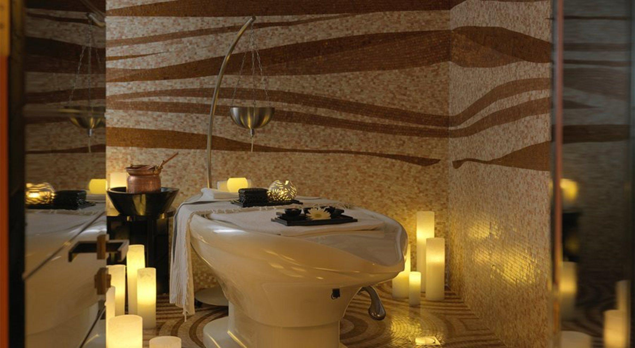 DAMAC Maison Dubai Mall Street Exterior foto The photo shows a bathroom setting designed for relaxation and tranquility. There is a modern toilet in the foreground, accompanied by a small table that holds decorative items. Soft, ambient lighting comes from several candles placed around the spac