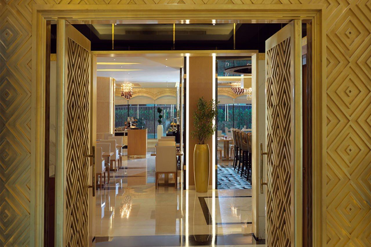 DAMAC Maison Dubai Mall Street Exterior foto The photo shows the entrance to a modern dining space or restaurant. The doors are designed with intricate geometric patterns and are open, revealing a well-lit interior. Inside, there are tables and chairs arranged for dining, with decorative lighti