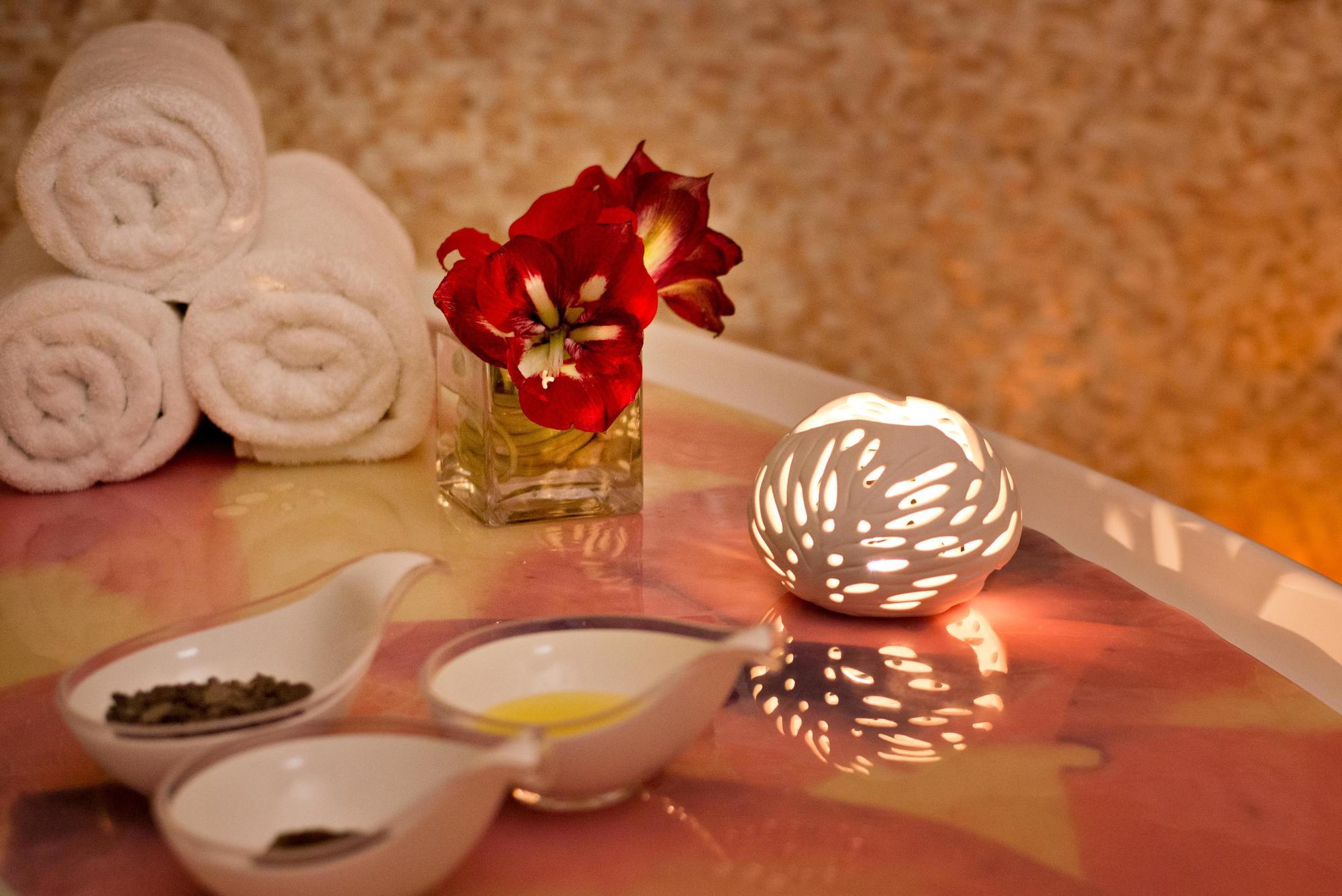 DAMAC Maison Dubai Mall Street Exterior foto The photo features a tranquil spa setting. In the foreground, there are three small white dishes containing various ingredients—one holds dark herbs or spices, another has a yellow substance, and the third appears empty. Behind these dishes, there is